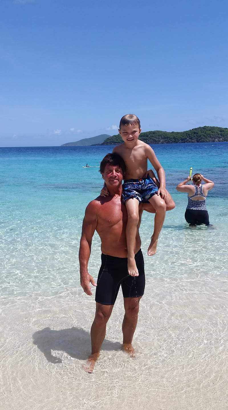 Bob at beach with child on his shoulder